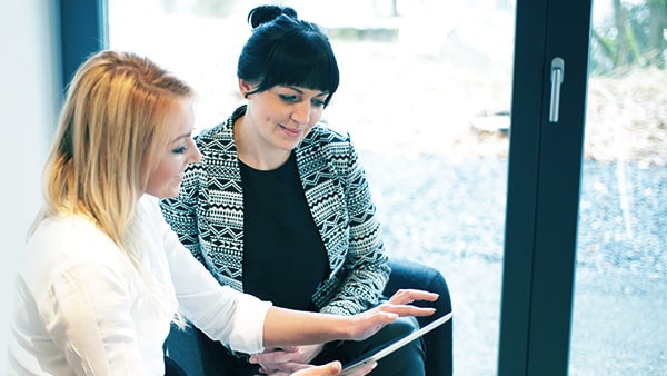 two women using a DMS on a tablet